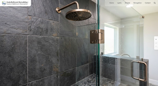 Walk-in shower design detail with brushed bronze fixture, slate wall tile, and frameless glass.